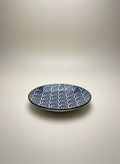 Assiette japonaise artisanale avec motif seigaiha vagues bleues concentriques sur fond blanc, extérieur noir profond céramique bicolore