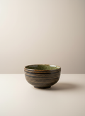Bol japonais artisanal brun foncé avec intérieur vert olive sur fond uni luxe