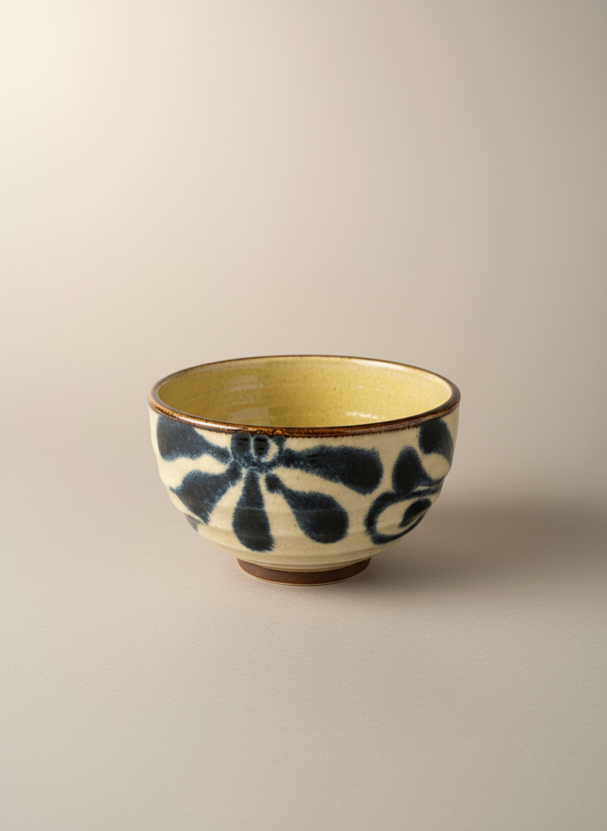 Bol japonais artisanal céramique extérieur crème avec motifs floraux végétaux noirs expressifs, intérieur glaçure dorée jaune contraste audacieux