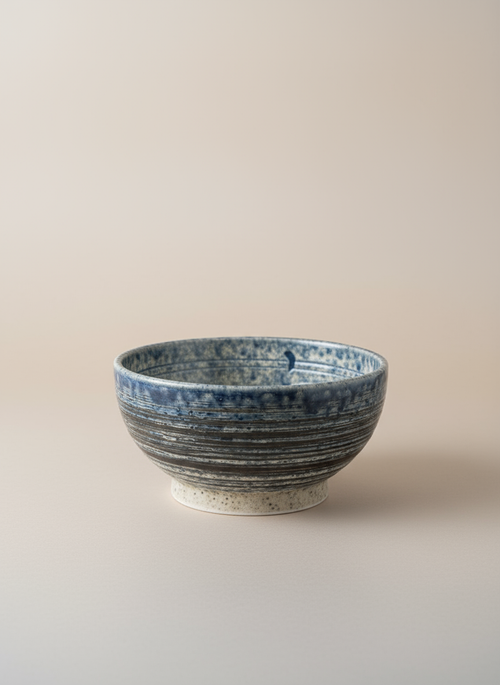 Bol japonais artisanal sur pied bleu foncé noir avec bandes horizontales texturées et intérieur crème moucheté céramique wabi-sabi